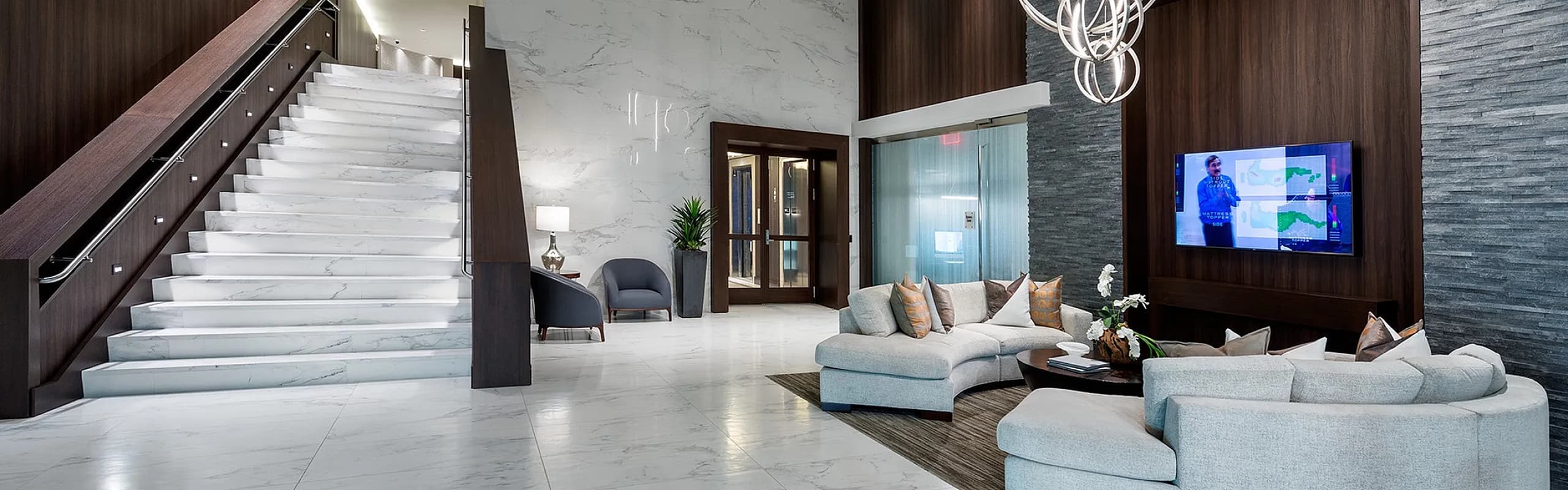 Luxurious lobby featuring elegant marble flooring, modern chandelier, and stylish seating area with sleek dark wood accents.