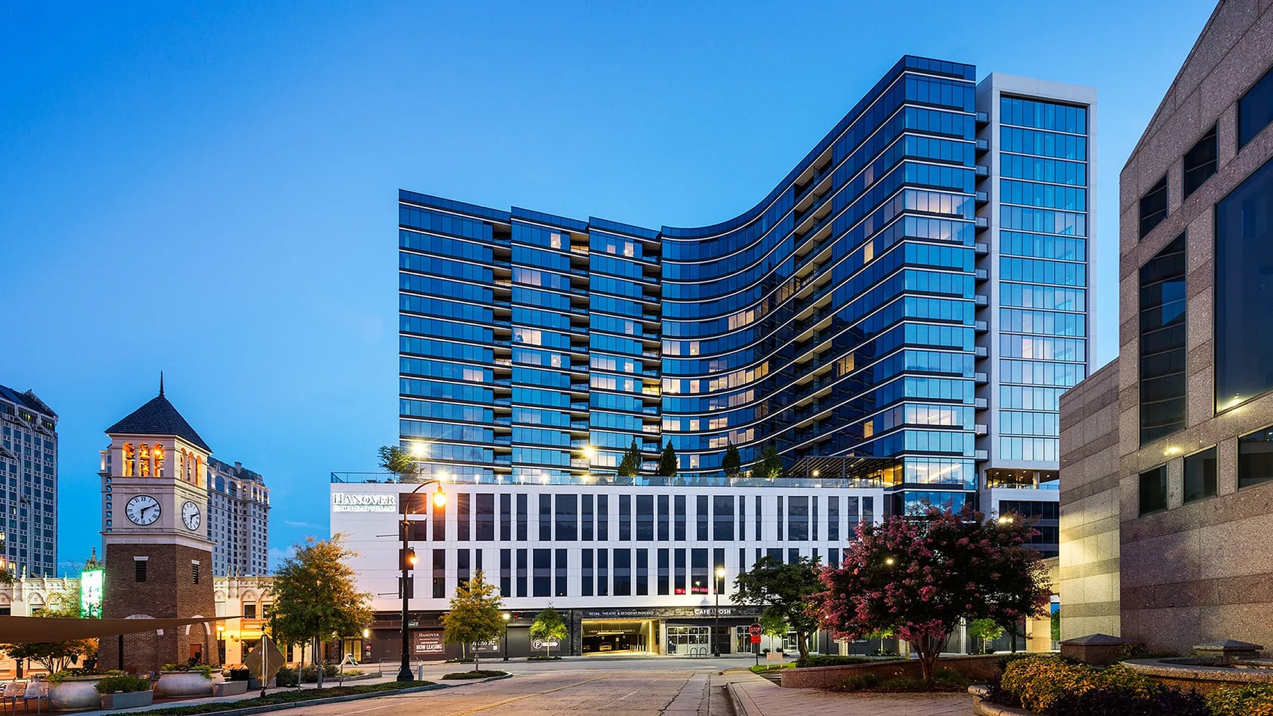 Modern high-rise building with sleek glass facade and vibrant cityscape in the evening light.