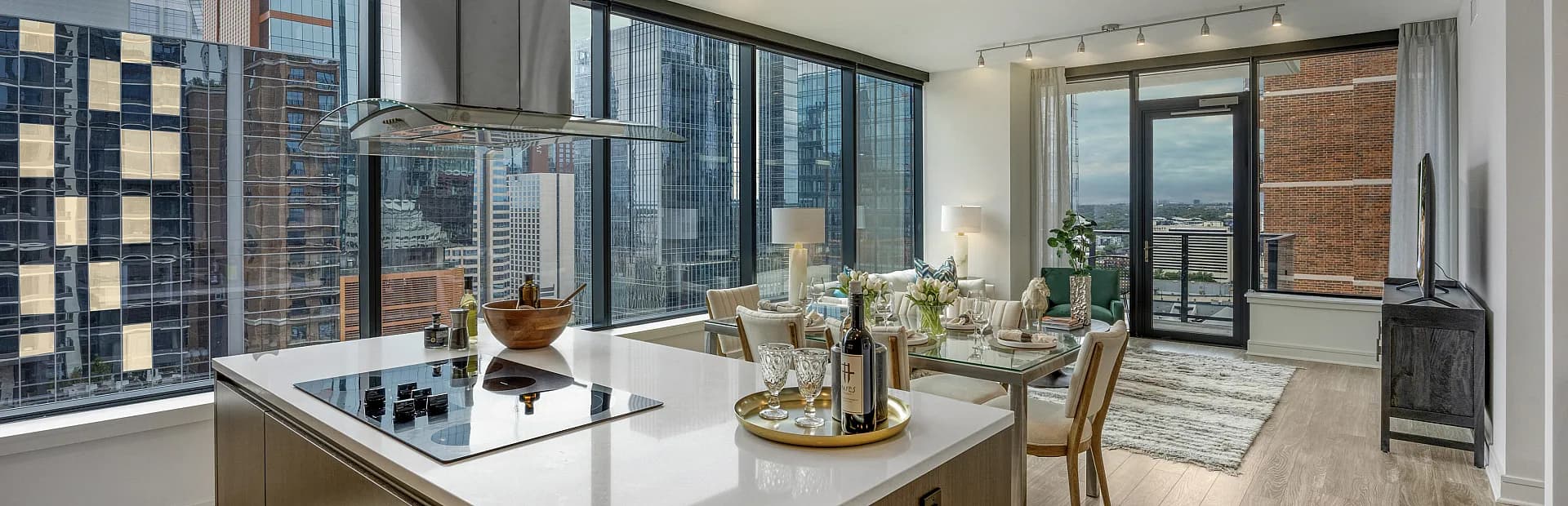 Modern city apartment with open-concept kitchen and dining area, featuring panoramic floor-to-ceiling windows and sleek contemporary design.