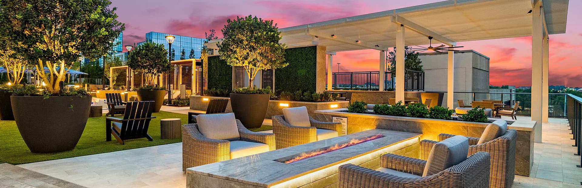 Luxurious rooftop terrace at sunset with cozy seating, elegant firepit, and lush greenery, perfect for relaxation and entertaining.