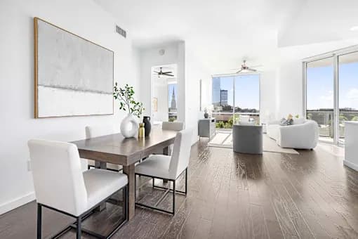 A modern dining room with a wooden table and white chairs.