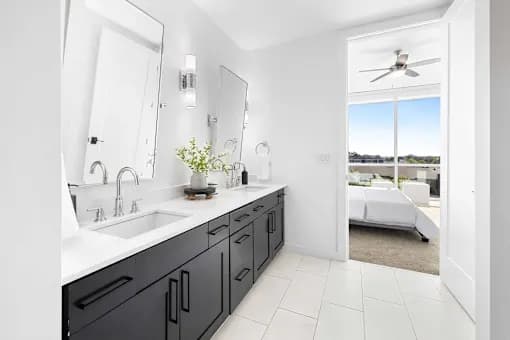 A bathroom with a black vanity and a white ceiling fan.