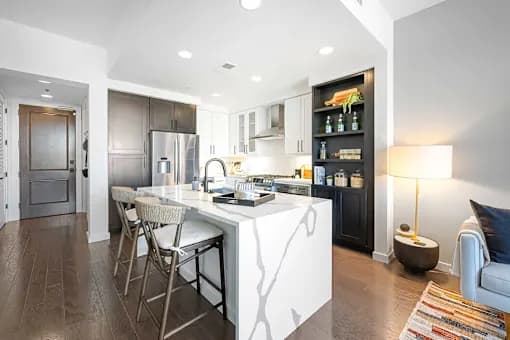 A modern kitchen with a white island and dark wood floors.
