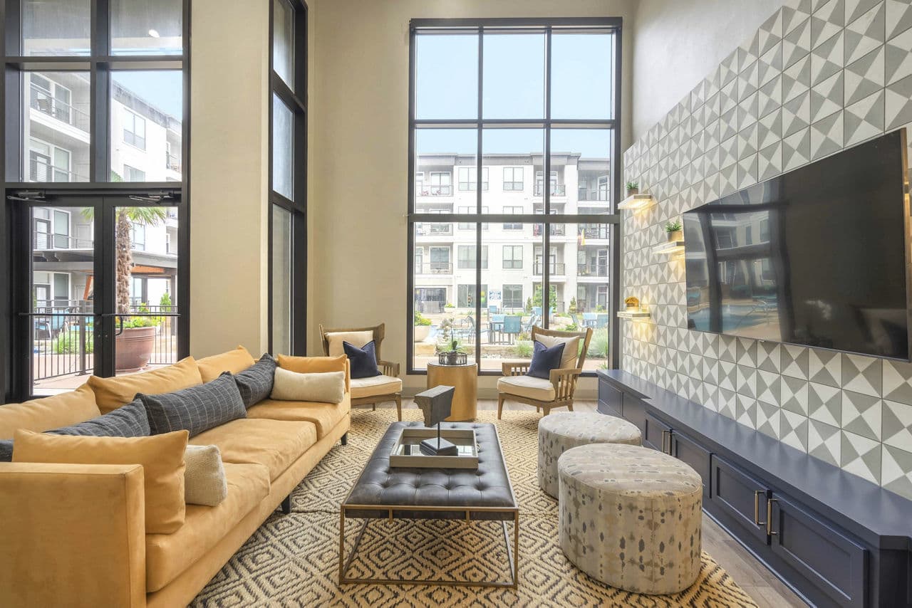 Modern clubhouse with cozy seating and large TV at Seville Uptown Apartments