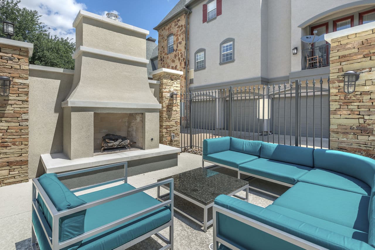 Patio area with cozy seating and lush greenery at Manchester State Thomas Apartments, offering a relaxing outdoor space in this luxury community