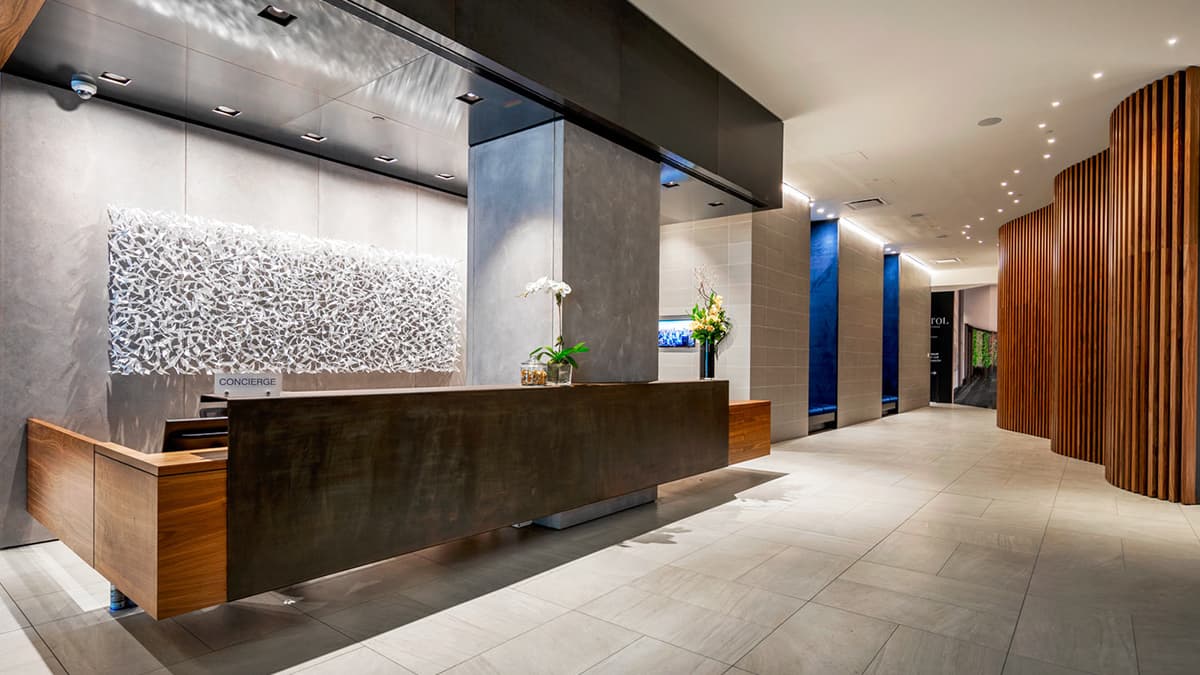 Building lobby with high ceilings, marble floor and large stone column next to wood reception desk