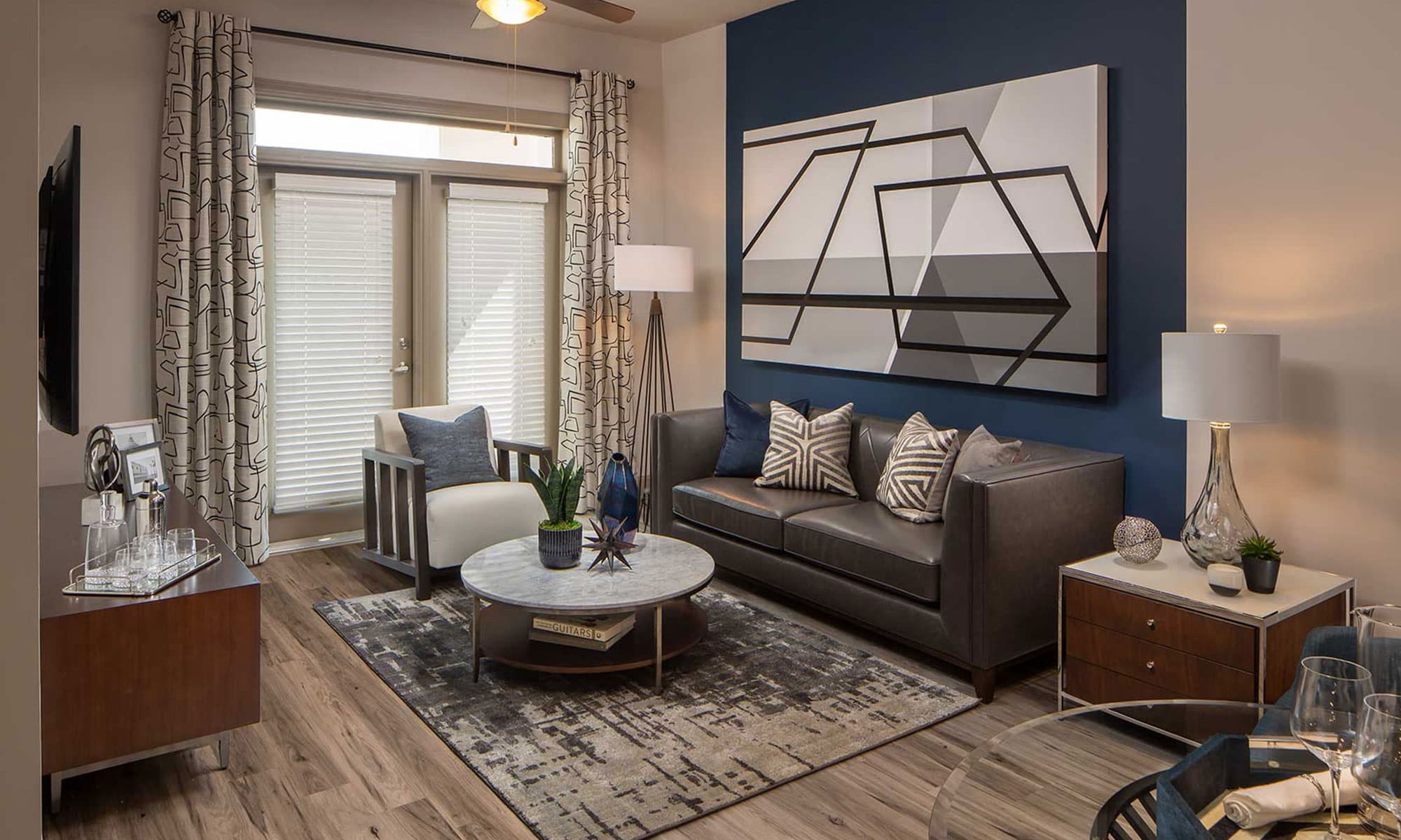 Living area with accent wall, wood like floors, double doors to patio, and typical furniture