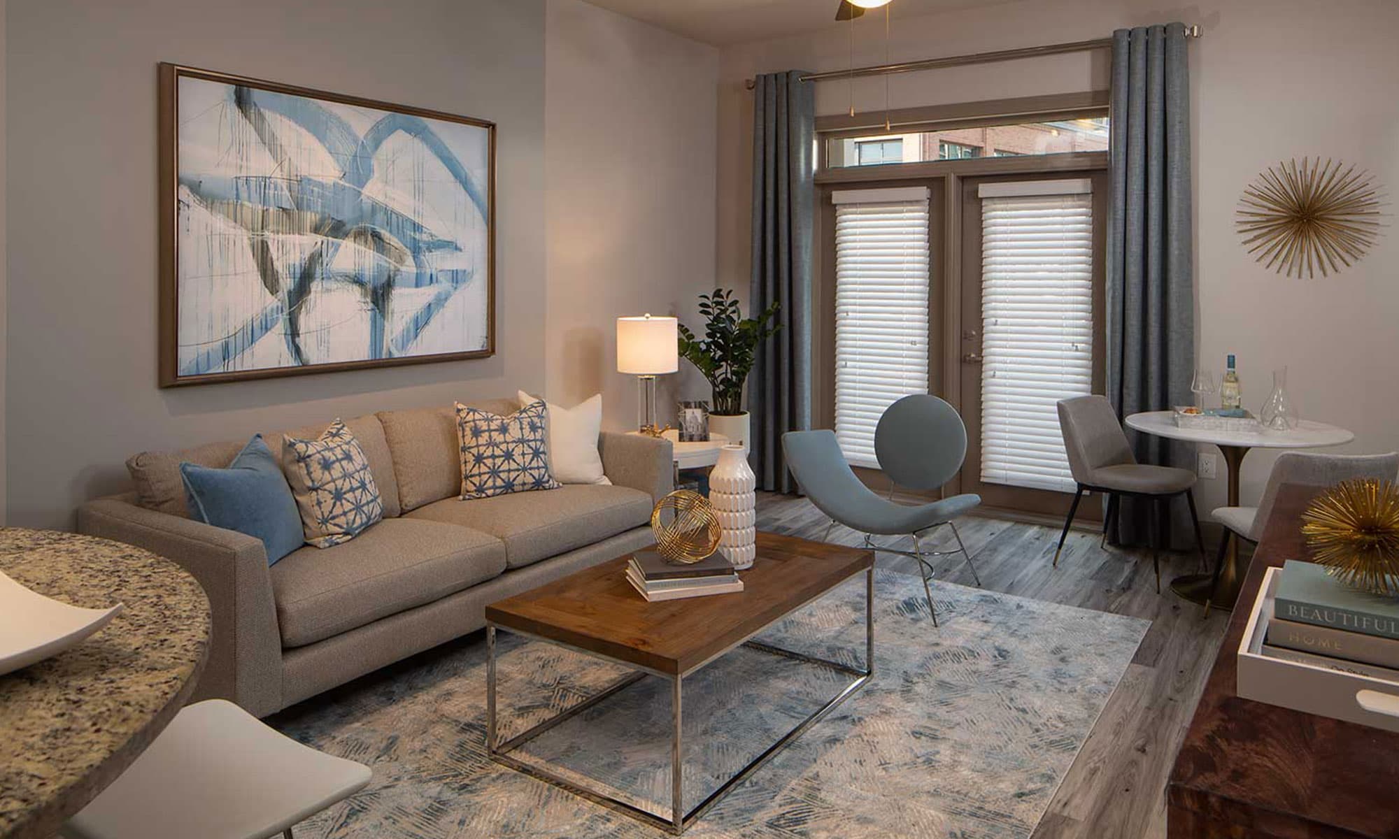 Living room with double doors to patio, wood like flooring, couch, coffee table and additional seating