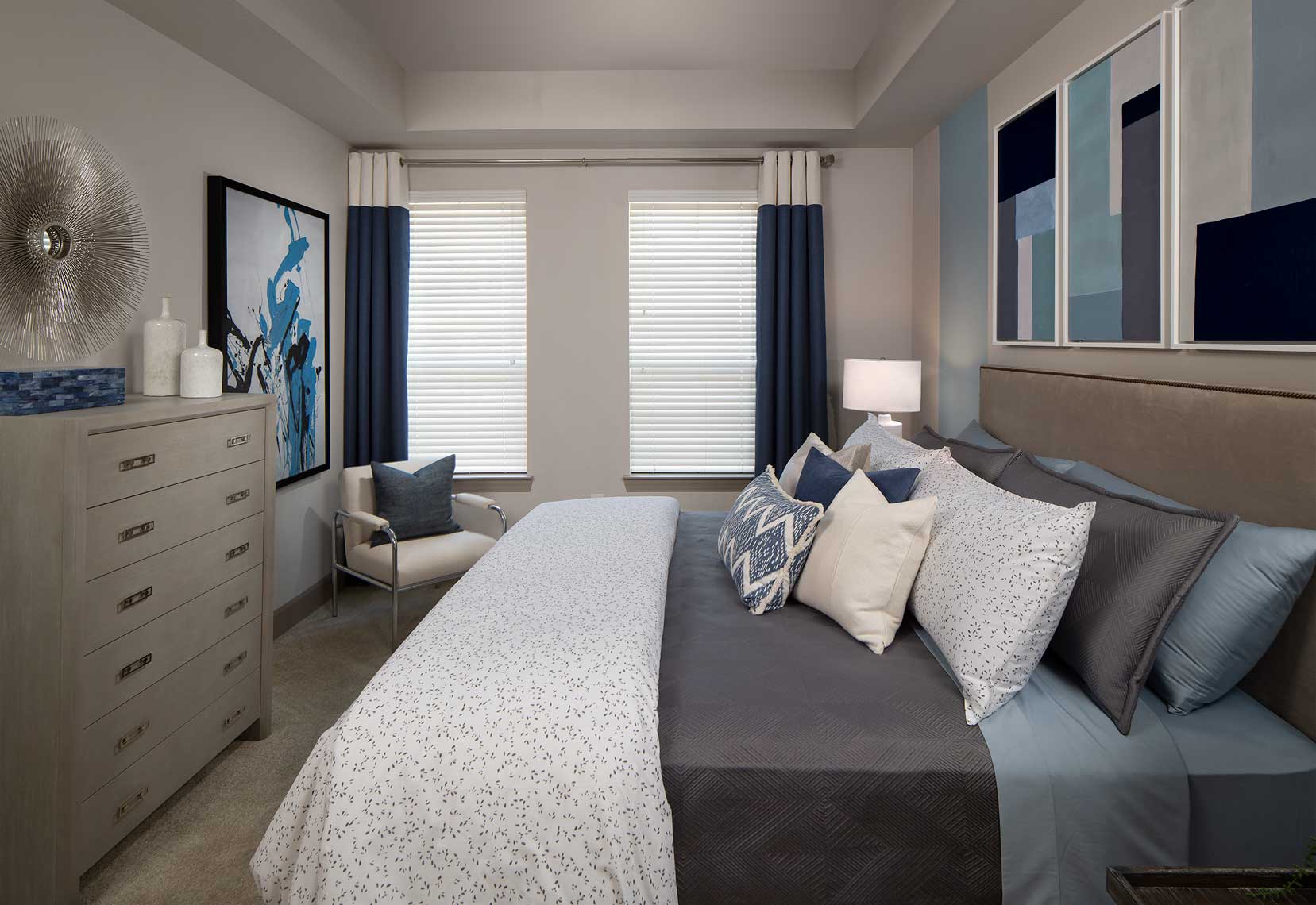 Bedroom with plush carpet, large windows, king sized bed, nightstands and dresser