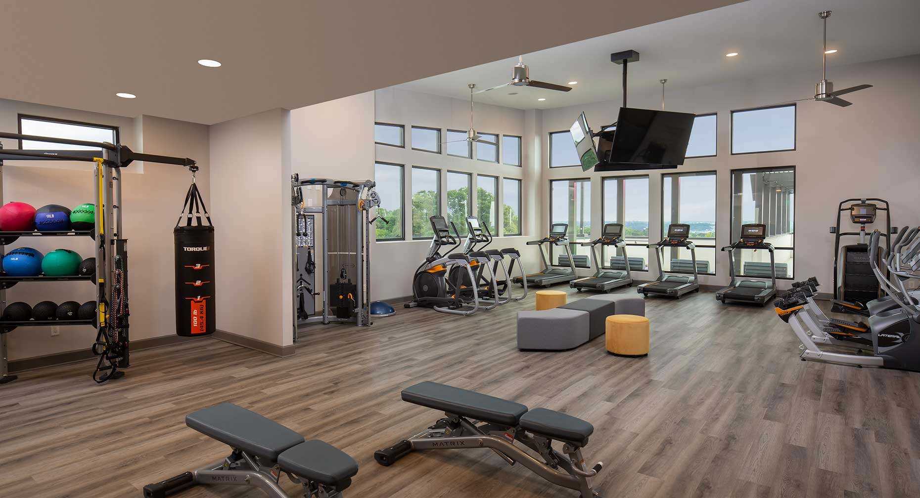 fitness center with tvs, treadmills, medicine balls, boxing bag, and other various equipment