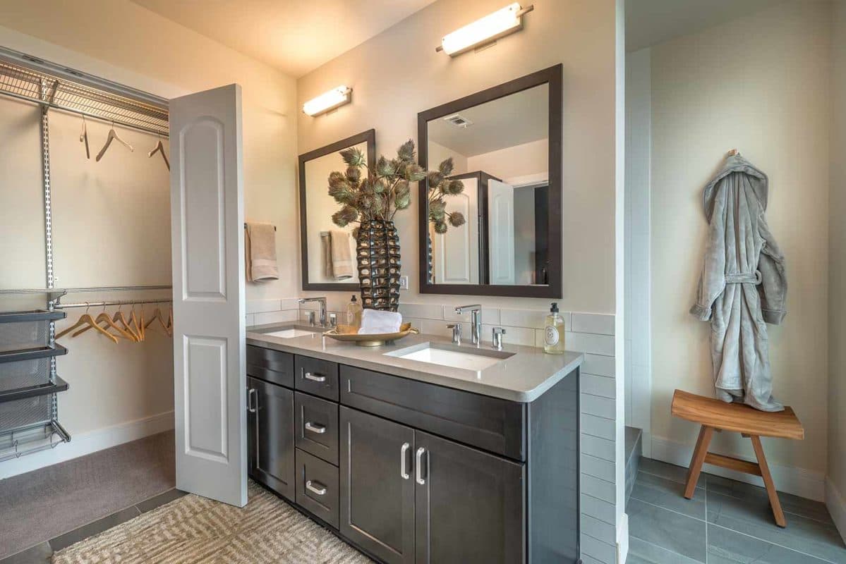 Bathroom with large closets, dark cabinetry and framed mirrors
