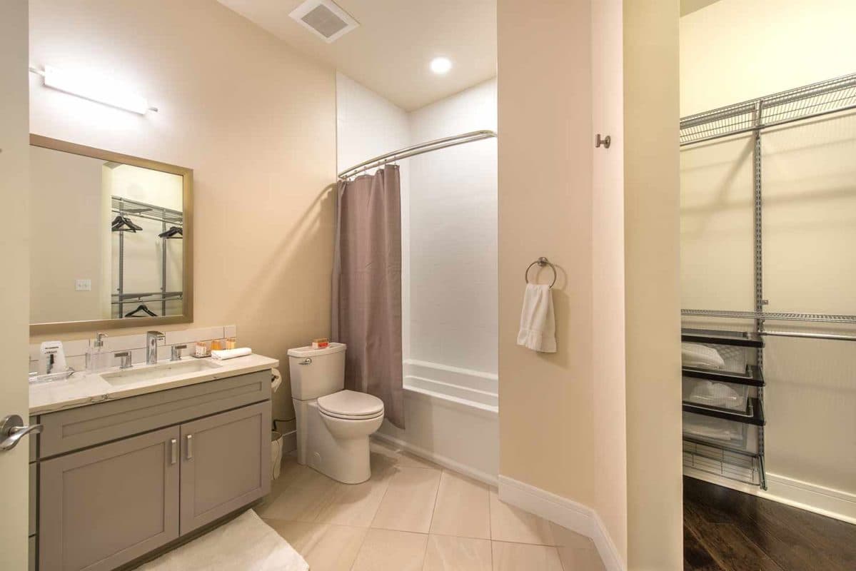 Spacious bathroom with carrara quartz counters and grey cabinetry
