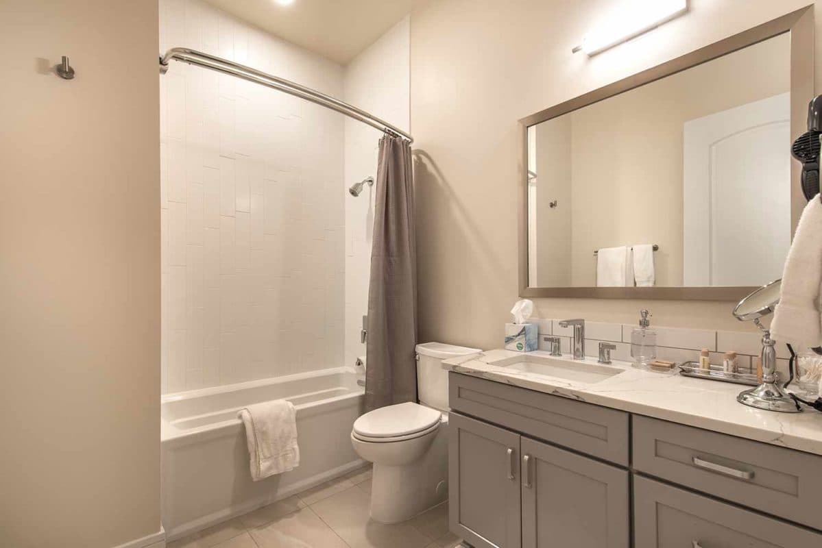 Spacious bathroom with carrara quartz counters and grey cabinetry