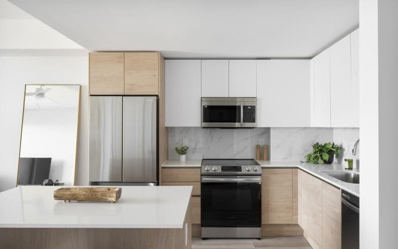 a kitchen with white cabinets a white island a stovetop a sink and a fridge