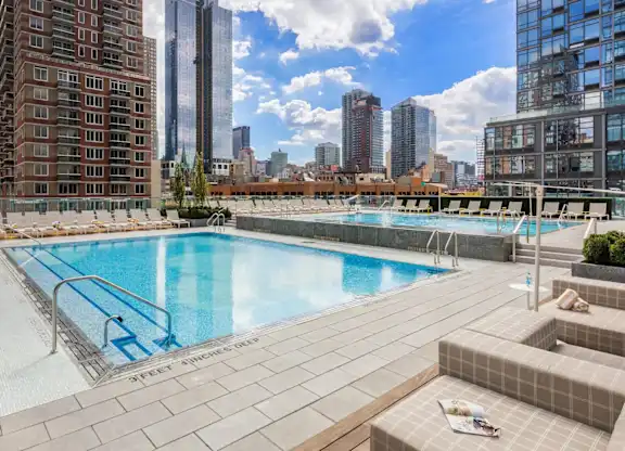 Rooftop swimming pool with skyline views and sun loungers at SKY Apartments, New York, NY 10036